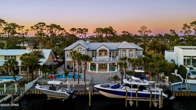 4522 Bay Point Rd, Panama City Beach, FL 32408 - back of property at dusk featuring an outdoor pool, a patio area, a balcony, metal roof, and boat lift