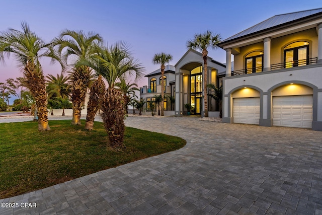 4522 Bay Point Rd, Panama City Beach, FL 32408 - view of front of house with stucco siding, an attached garage, a balcony, a front lawn, and decorative driveway