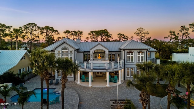 4522 Bay Point Rd, Panama City Beach, FL 32408 - rear view of house featuring a standing seam roof, metal roof, a balcony, a patio area, and a chimney