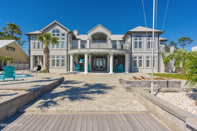4522 Bay Point Rd, Panama City Beach, FL 32408 - rear view of house with stucco siding, fence, a patio, french doors, and a balcony