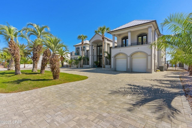 4522 Bay Point Rd, Panama City Beach, FL 32408 - mediterranean / spanish-style home with stucco siding, a balcony, metal roof, decorative driveway, and a garage