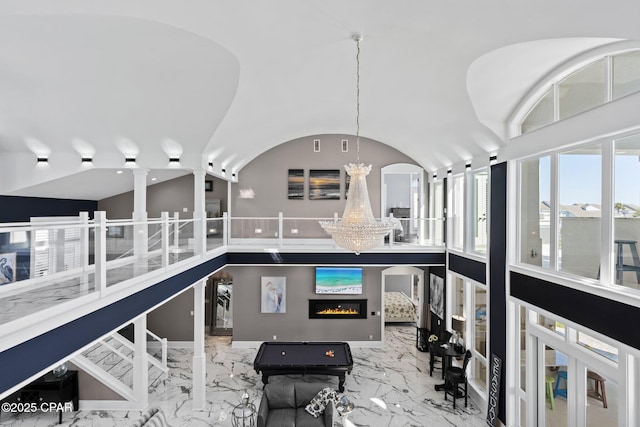 4522 Bay Point Rd, Panama City Beach, FL 32408 - living room featuring a glass covered fireplace, lofted ceiling, an inviting chandelier, marble finish floor, and ornate columns