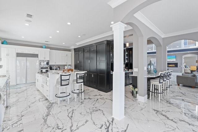 4522 Bay Point Rd, Panama City Beach, FL 32408 - kitchen featuring white cabinets, a kitchen bar, built in appliances, and visible vents