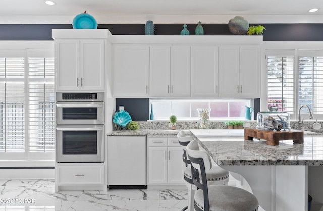 4522 Bay Point Rd, Panama City Beach, FL 32408 - kitchen featuring white cabinetry, marble finish floor, stainless steel double oven, and light stone counters
