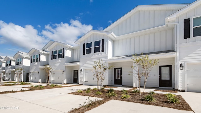 multi unit property featuring a residential view, board and batten siding, an attached garage, and driveway