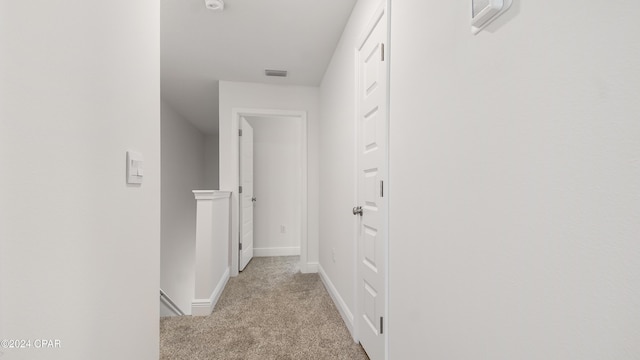 corridor with visible vents, baseboards, and light carpet