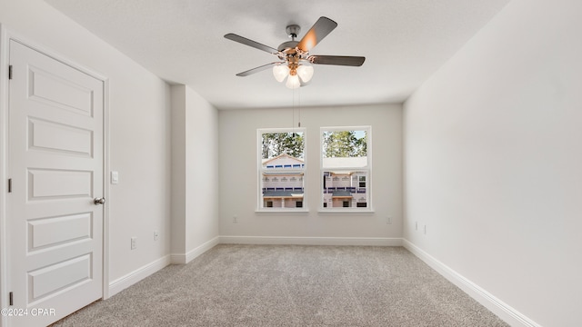 empty room with ceiling fan, baseboards, and carpet