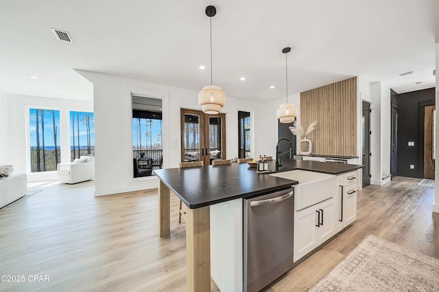 7603 Coastal Hammock Trl, Panama City Beach, FL 32413 - kitchen featuring dishwasher, dark countertops, light wood-type flooring, a center island with sink, and healthy amount of natural light
