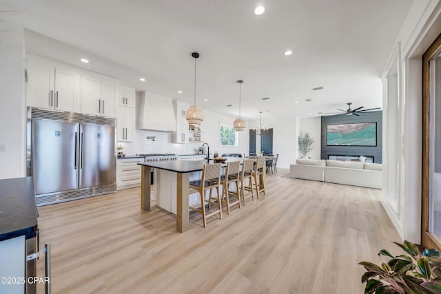 7603 Coastal Hammock Trl, Panama City Beach, FL 32413 - kitchen with built in fridge, dark countertops, premium range hood, recessed lighting, and light wood-type flooring