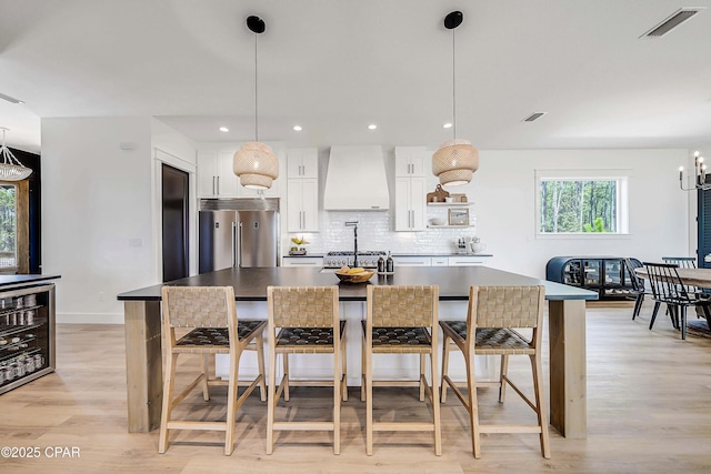 7603 Coastal Hammock Trl, Panama City Beach, FL 32413 - kitchen featuring high quality fridge, custom exhaust hood, a large island with sink, light wood-style floors, and a kitchen bar