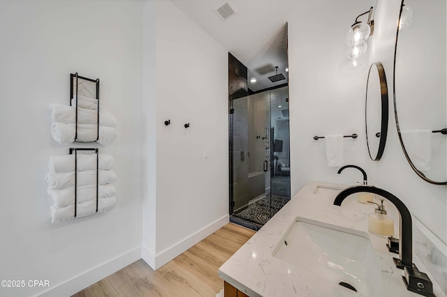 7603 Coastal Hammock Trl, Panama City Beach, FL 32413 - full bathroom with double vanity, a shower stall, baseboards, and wood finished floors
