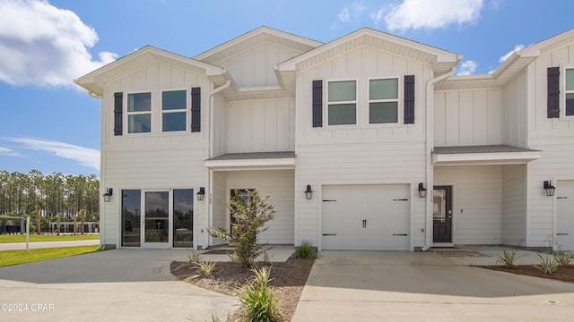 townhome / multi-family property with board and batten siding, concrete driveway, and a garage