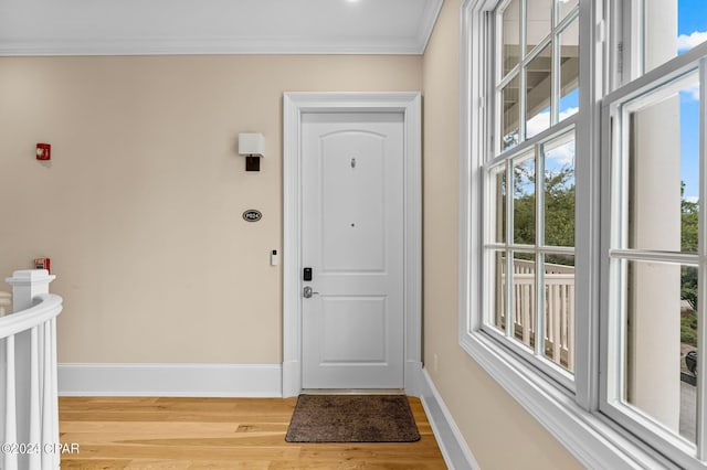 foyer featuring wood finished floors, baseboards, and ornamental molding