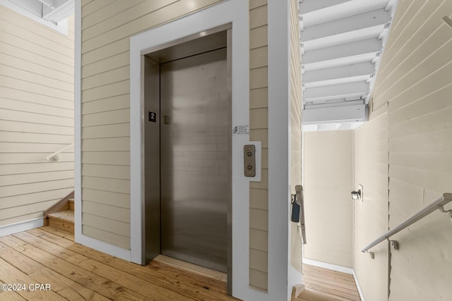 bathroom with elevator, wood finished floors, and wooden walls