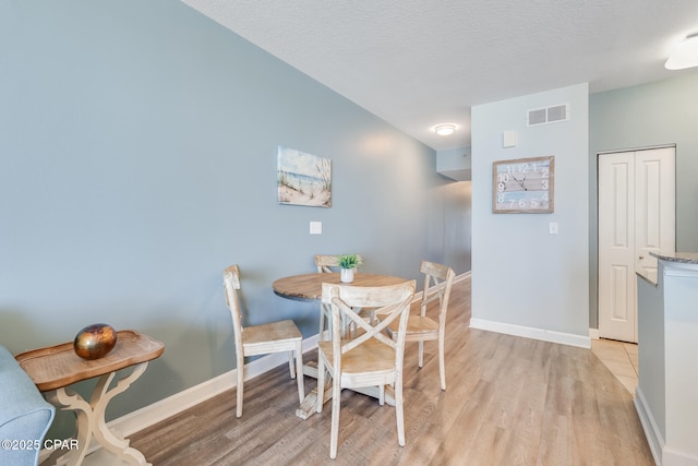 dining area with light wood finished floors, baseboards, and visible vents