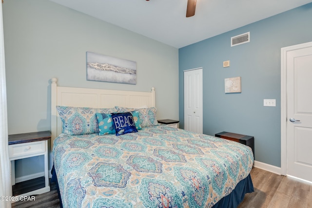 bedroom featuring a closet, visible vents, baseboards, ceiling fan, and wood finished floors