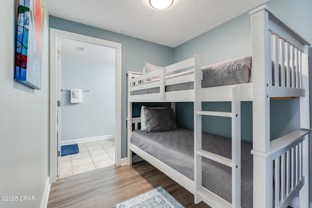 bedroom with baseboards, visible vents, and wood finished floors