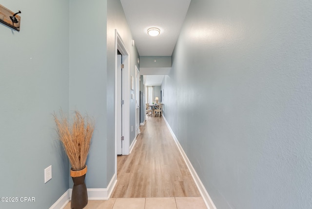 hall featuring light tile patterned floors and baseboards