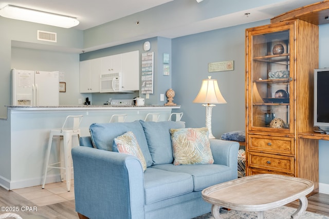 living room featuring light wood-style flooring, baseboards, and visible vents