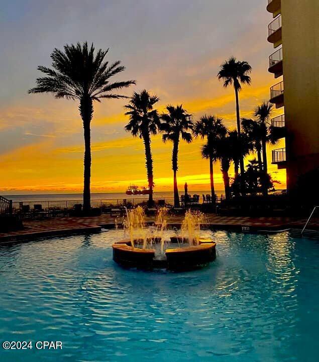pool at dusk featuring a water view