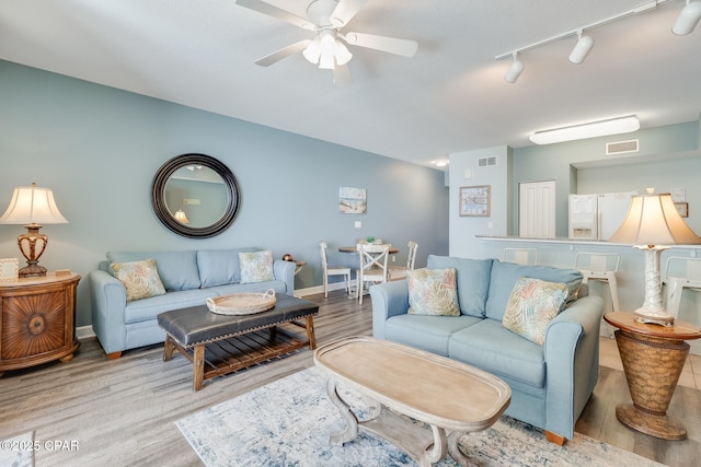 living room featuring a ceiling fan, wood finished floors, baseboards, and visible vents