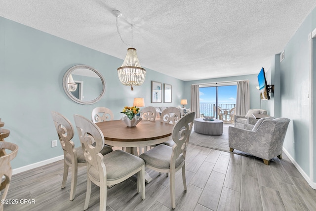 5801 Thomas Dr Unit 1216, Panama City Beach, FL 32408 - dining room featuring an inviting chandelier, a textured ceiling, light wood-style floors, and baseboards