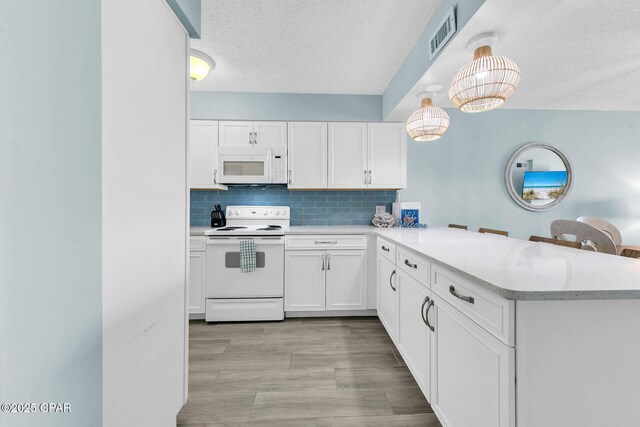 5801 Thomas Dr Unit 1216, Panama City Beach, FL 32408 - kitchen with tasteful backsplash, white appliances, a peninsula, white cabinets, and a textured ceiling