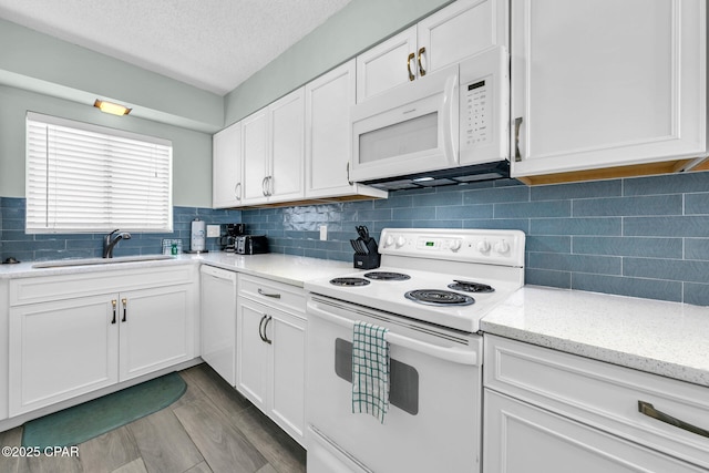 5801 Thomas Dr Unit 1216, Panama City Beach, FL 32408 - kitchen featuring a sink, decorative backsplash, light stone counters, white cabinetry, and white appliances