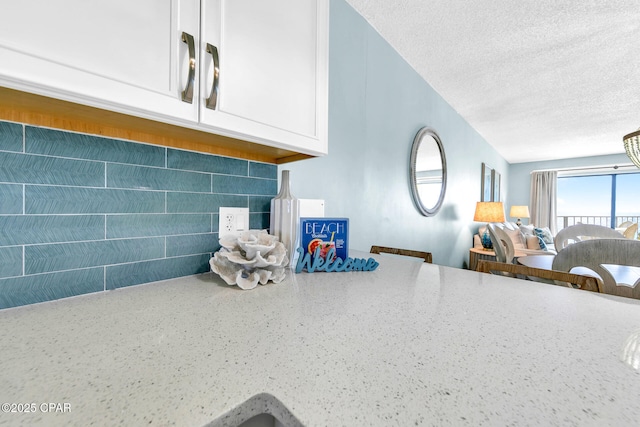 5801 Thomas Dr Unit 1216, Panama City Beach, FL 32408 - details featuring a textured ceiling, white cabinets, backsplash, and light stone countertops