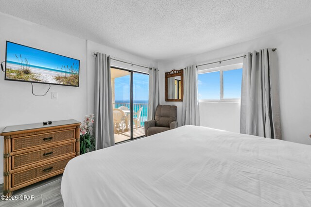 5801 Thomas Dr Unit 1216, Panama City Beach, FL 32408 - bedroom with access to exterior, a textured ceiling, wood finished floors, and a water view