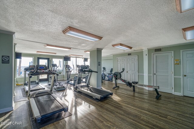 5801 Thomas Dr Unit 1216, Panama City Beach, FL 32408 - workout area featuring a textured ceiling, visible vents, wood finished floors, and baseboards