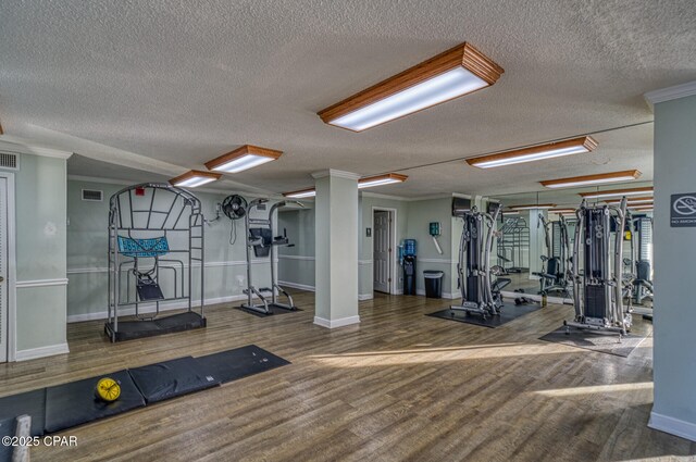 5801 Thomas Dr Unit 1216, Panama City Beach, FL 32408 - gym with crown molding, visible vents, baseboards, a textured ceiling, and wood finished floors