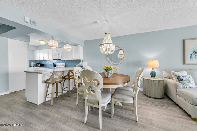 5801 Thomas Dr Unit 1216, Panama City Beach, FL 32408 - dining room with light wood-style floors, a notable chandelier, and a textured ceiling