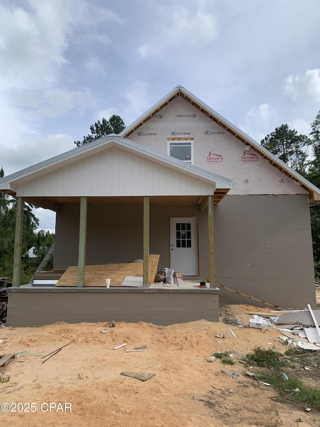 back of property with covered porch and concrete block siding