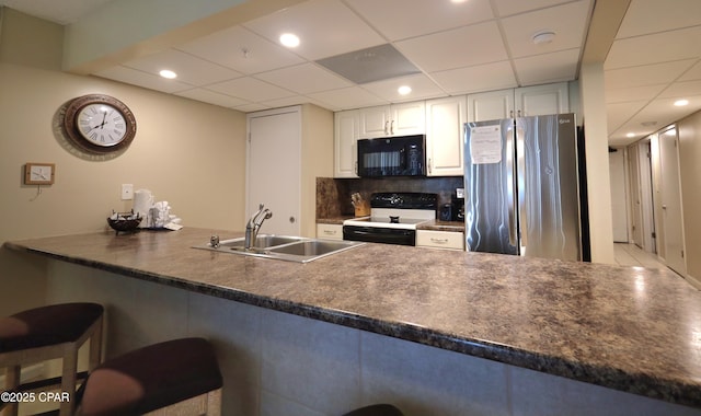 kitchen with freestanding refrigerator, black microwave, range with electric stovetop, a sink, and dark countertops