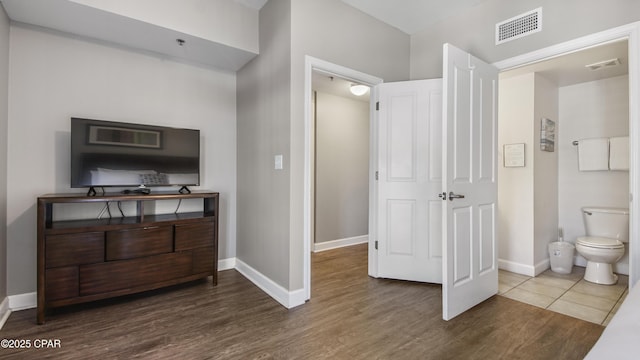 bathroom featuring toilet, wood finished floors, baseboards, and visible vents