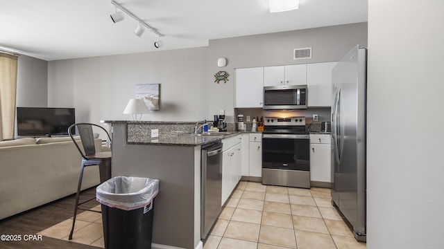 9900 S Thomas Dr Unit 1719, Panama City Beach, FL 32408 - kitchen featuring stainless steel appliances, a peninsula, white cabinetry, open floor plan, and a kitchen bar