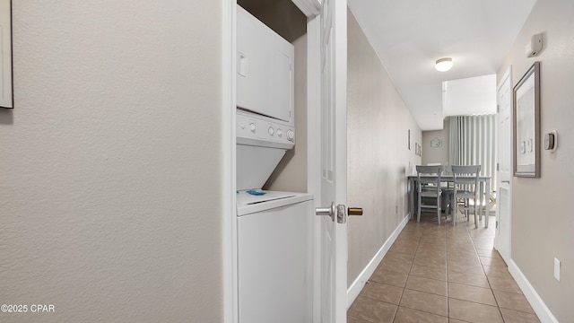corridor featuring stacked washer / drying machine and light tile patterned floors