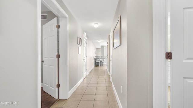 corridor featuring light tile patterned floors and baseboards