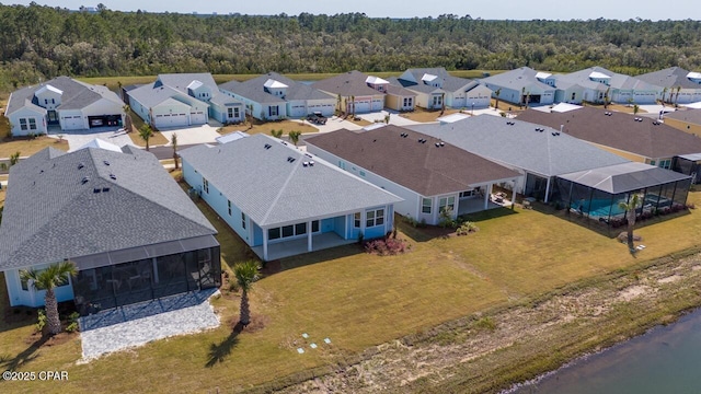 drone / aerial view featuring a wooded view and a residential view