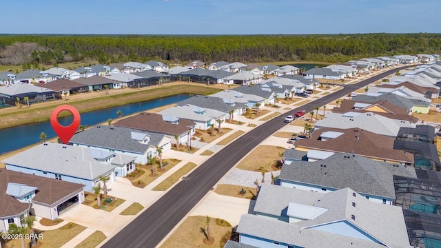 drone / aerial view with a water view, a residential view, and a forest view