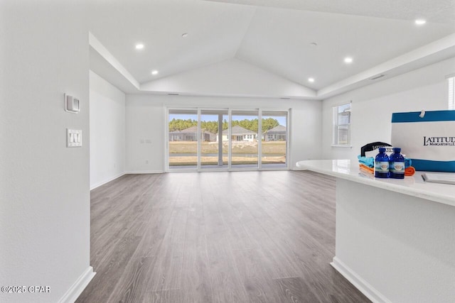 unfurnished living room featuring baseboards, wood finished floors, and vaulted ceiling