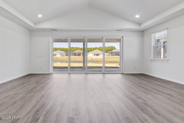 spare room featuring wood finished floors, lofted ceiling, and plenty of natural light