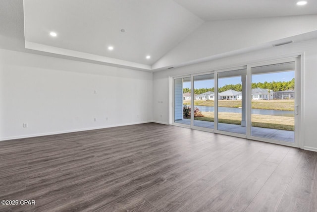 unfurnished room featuring baseboards, vaulted ceiling, recessed lighting, dark wood finished floors, and a water view