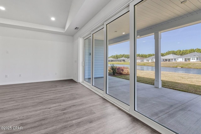 interior space with recessed lighting, a water view, wood finished floors, baseboards, and a residential view