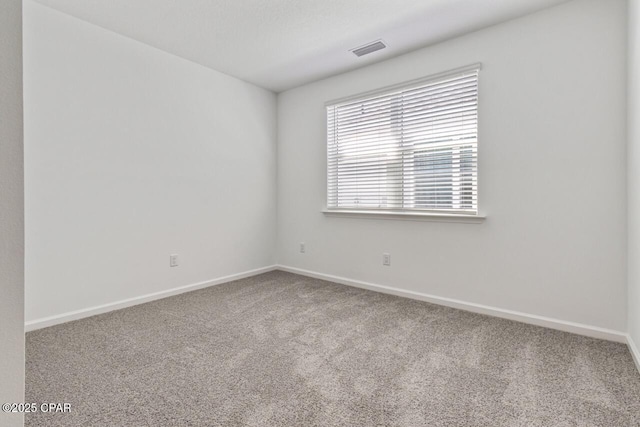 spare room featuring baseboards, visible vents, and carpet floors