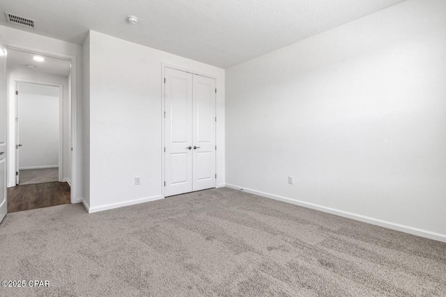 unfurnished bedroom with a closet, visible vents, baseboards, and carpet floors