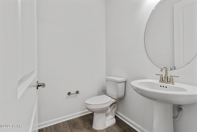 half bath with toilet, baseboards, and wood finished floors