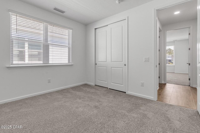 unfurnished bedroom featuring visible vents, a closet, baseboards, and carpet floors