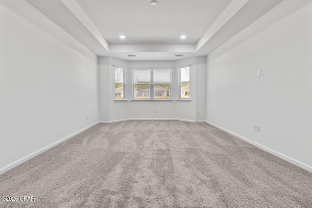 unfurnished room featuring recessed lighting, carpet flooring, a tray ceiling, and baseboards